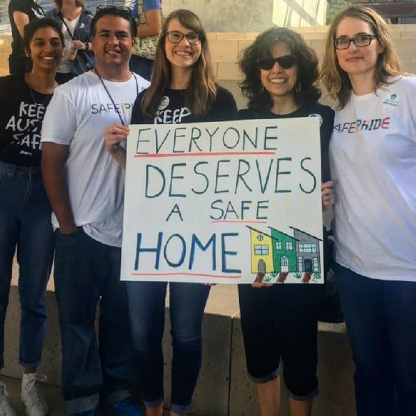 Cinco personas sosteniendo un cartel que dice &quot;Todos merecen un hogar seguro&quot;