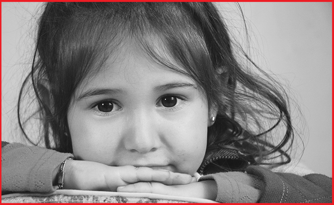 A black and white image of a young girl looking at the camera.