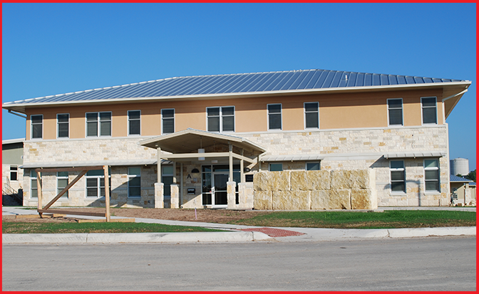 A photo of a tan office building. The words SAFE Children's Shelter are on a sign outside the building.