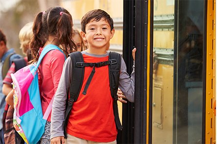 A young male identified student is boarding a school bus