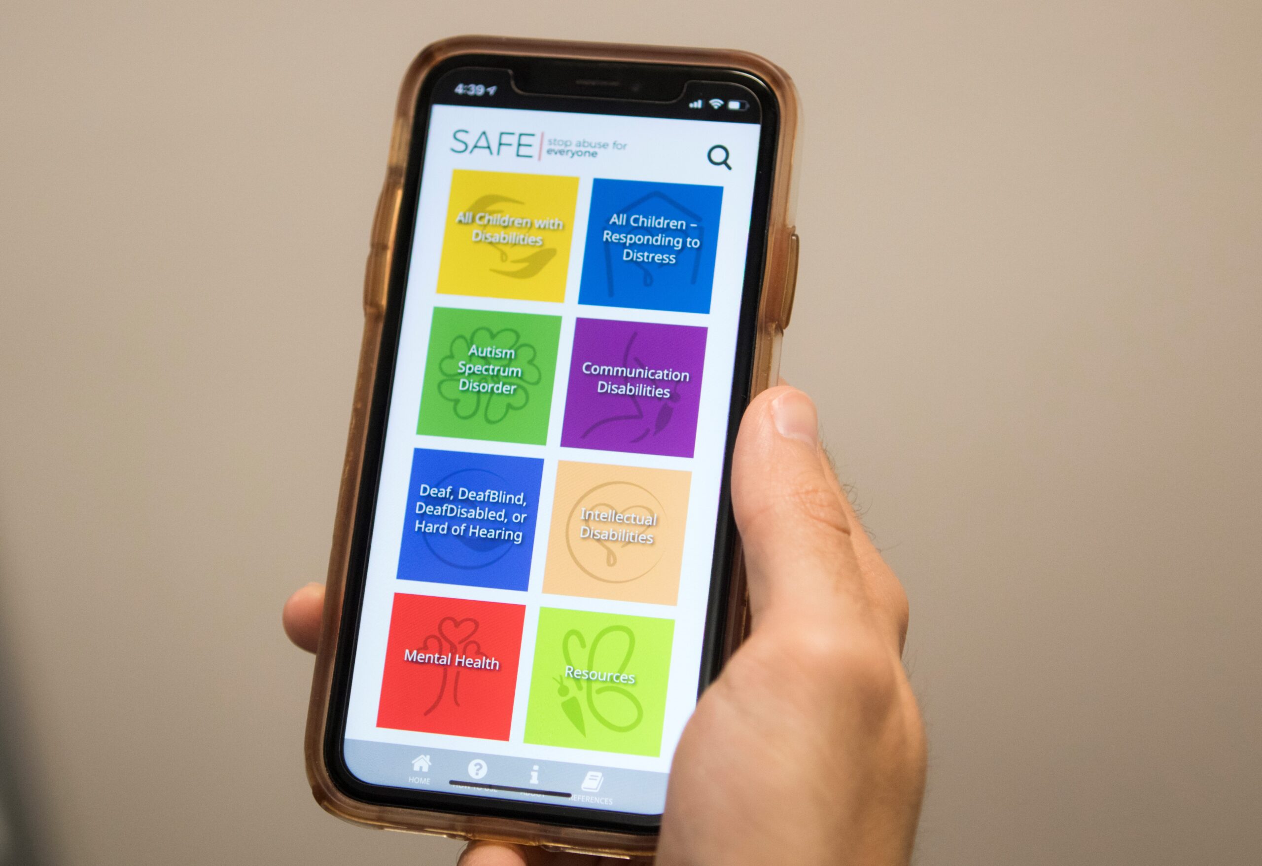 A photo of a cell cell phone in a hand. The phone displays several colorful icons.