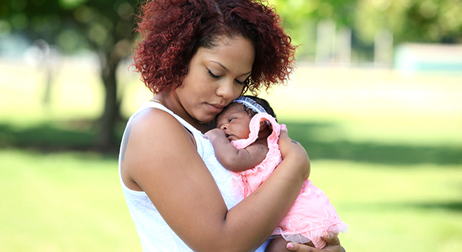 A photograph of a female-identified person holding a young child