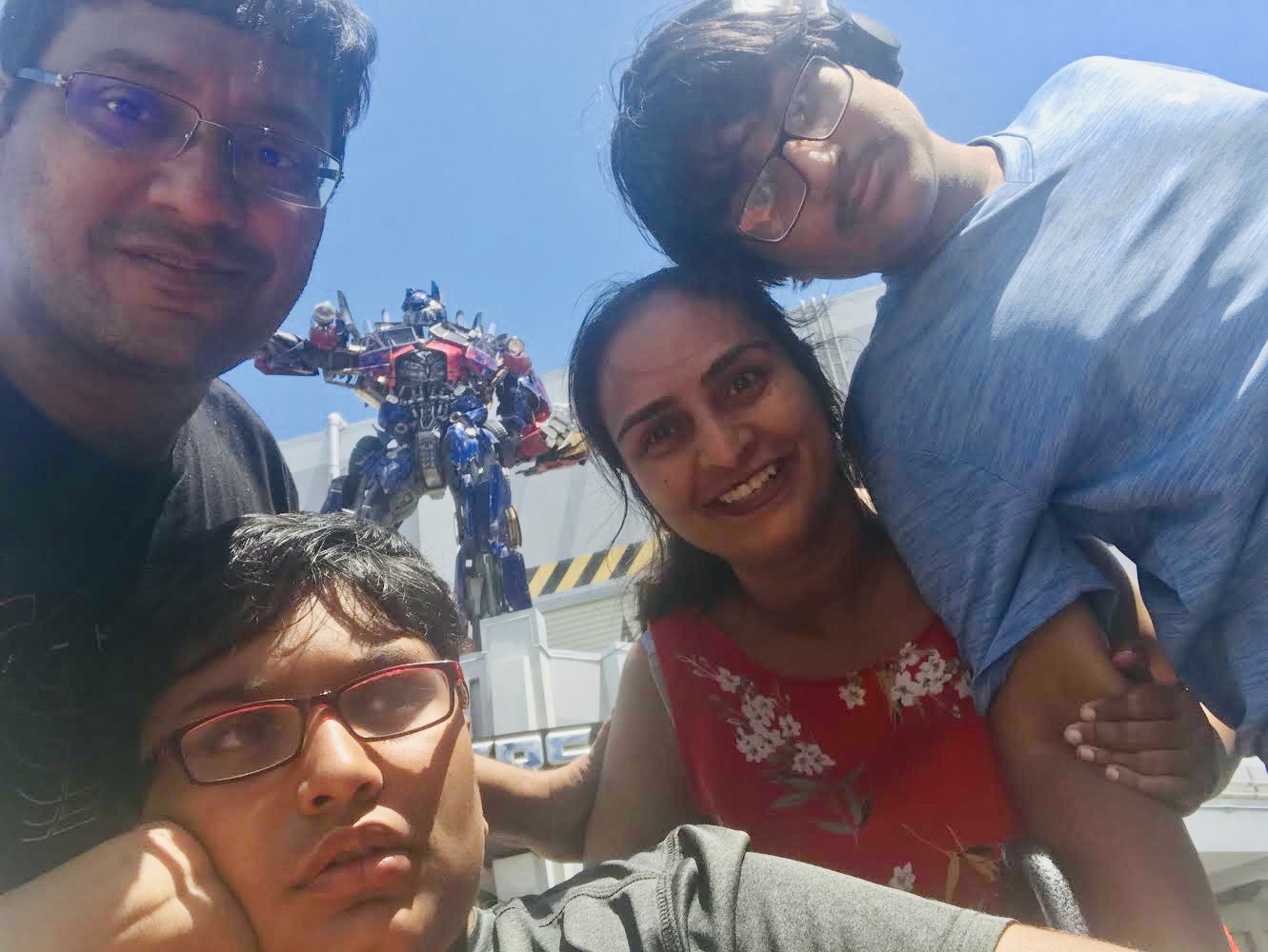 A family of four spending time outside together. A clear blue sky is in the background. The family is made up of two adults and two children.