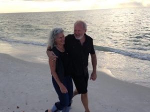 A photo of Paula and Kent Neiheisel. The couple are walking along a serene beach.