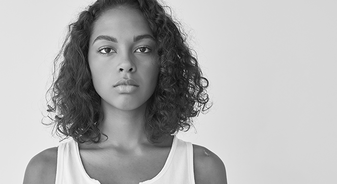 A black and white photo of a Black/African American woman looking at the camera.