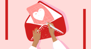 An illustration of a person's hands placing a letter in an envelope. The letter has a big, white cartoon heart on it. The envelope is red.