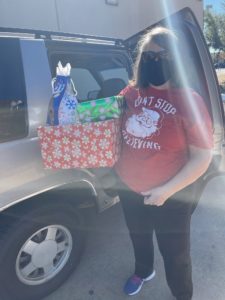 A photo of a person standing next to a car holding presents.