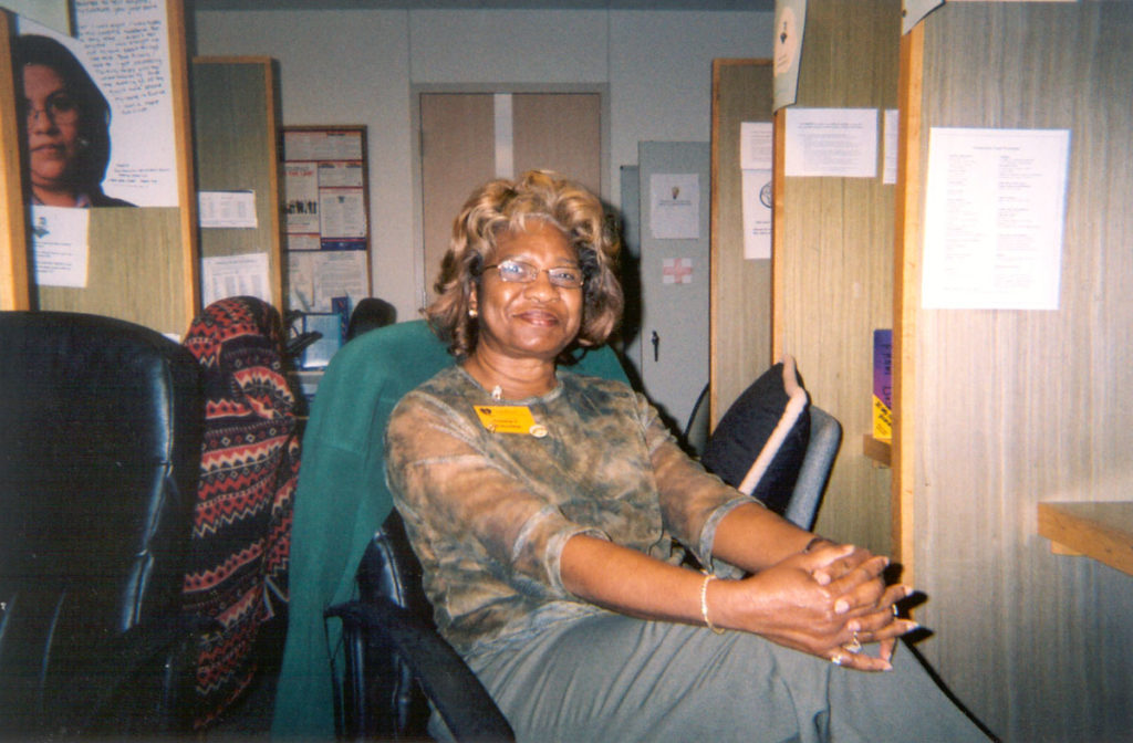 Image description: A photo of Frankie Fowler sitting at the former SafePlace shelter where she volunteered answering phone calls from people seeking support with family violence.