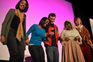 Descripción de la imagen: Una foto de los adolescentes del grupo de teatro juvenil Changing Lives durante una actuación en directo en el escenario. 