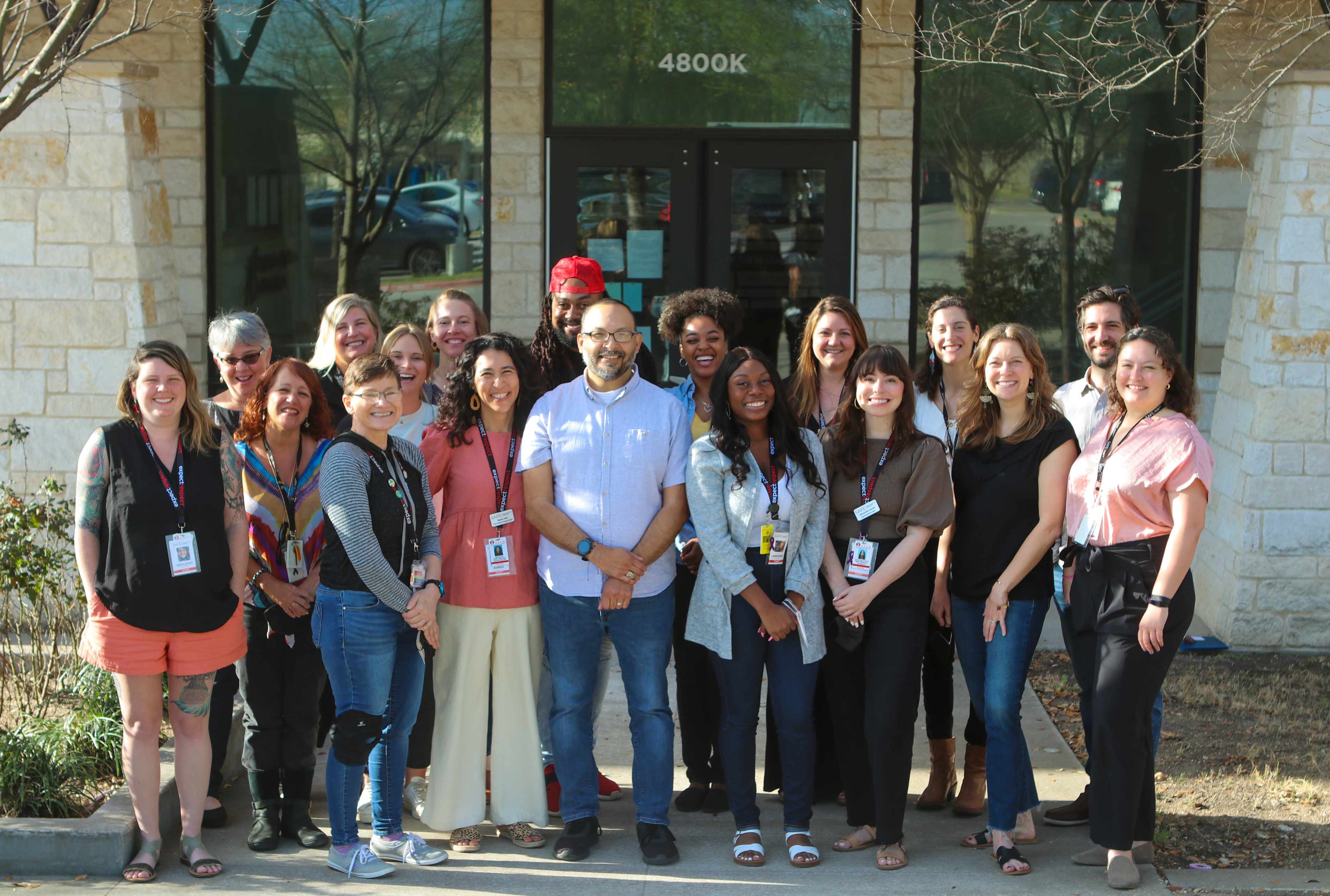 Descripción de la imagen: Una foto de más de una docena de personas de pie frente a la sede de SAFE en Austin, Texas. El grupo está formado en su mayoría por personal y ex personal de Expect Respect.