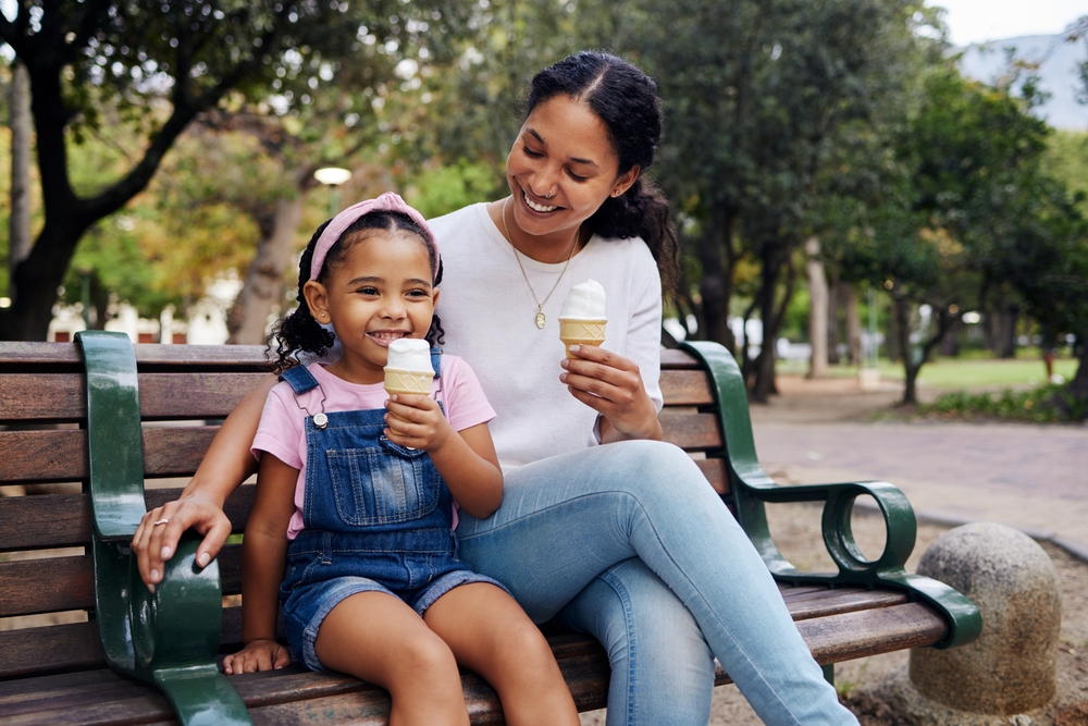 A mother and her child eating ice cream at the park.