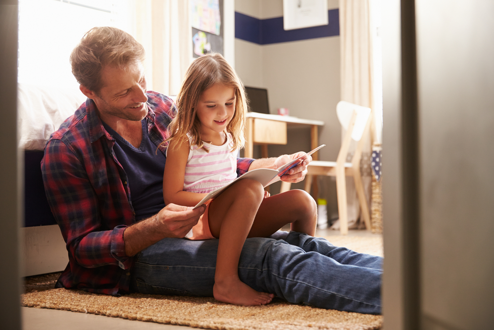 A father and his daughter reading a book together.