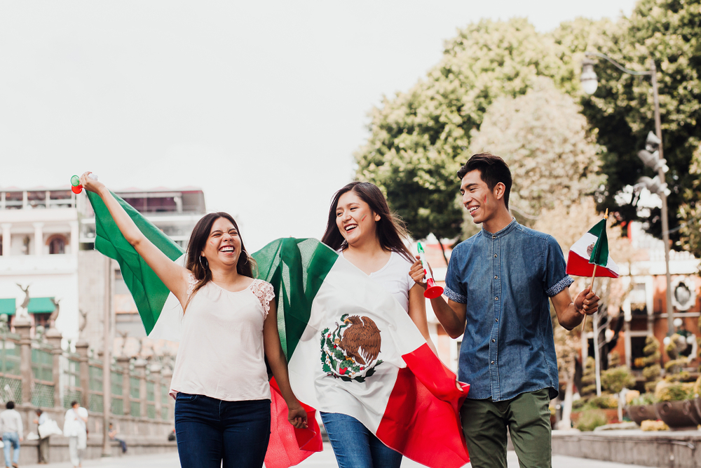 Three people holding Mexican flags.