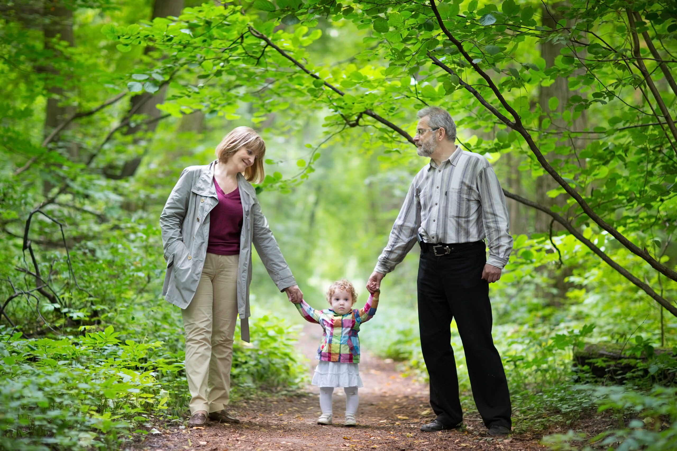 Older couple walking with little girl through the woods.