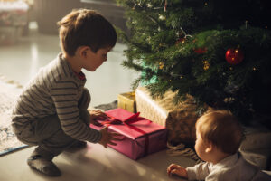 two small boys opening a few presents under a christmas tree | holiday gift donations | donate christmas gifts to kids | holiday donations for children | give gifts to kids in need | SAFE holiday giving guide | give gifts to kids in austin tx
